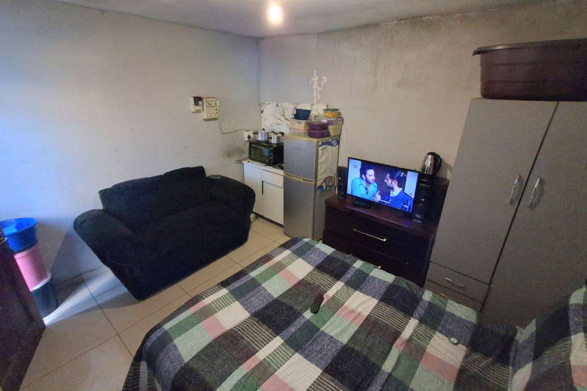 A compact bedroom featuring tiled flooring and basic built-in cabinetry, currently showing signs of wear and requiring cosmetic updates to the wall finishes.