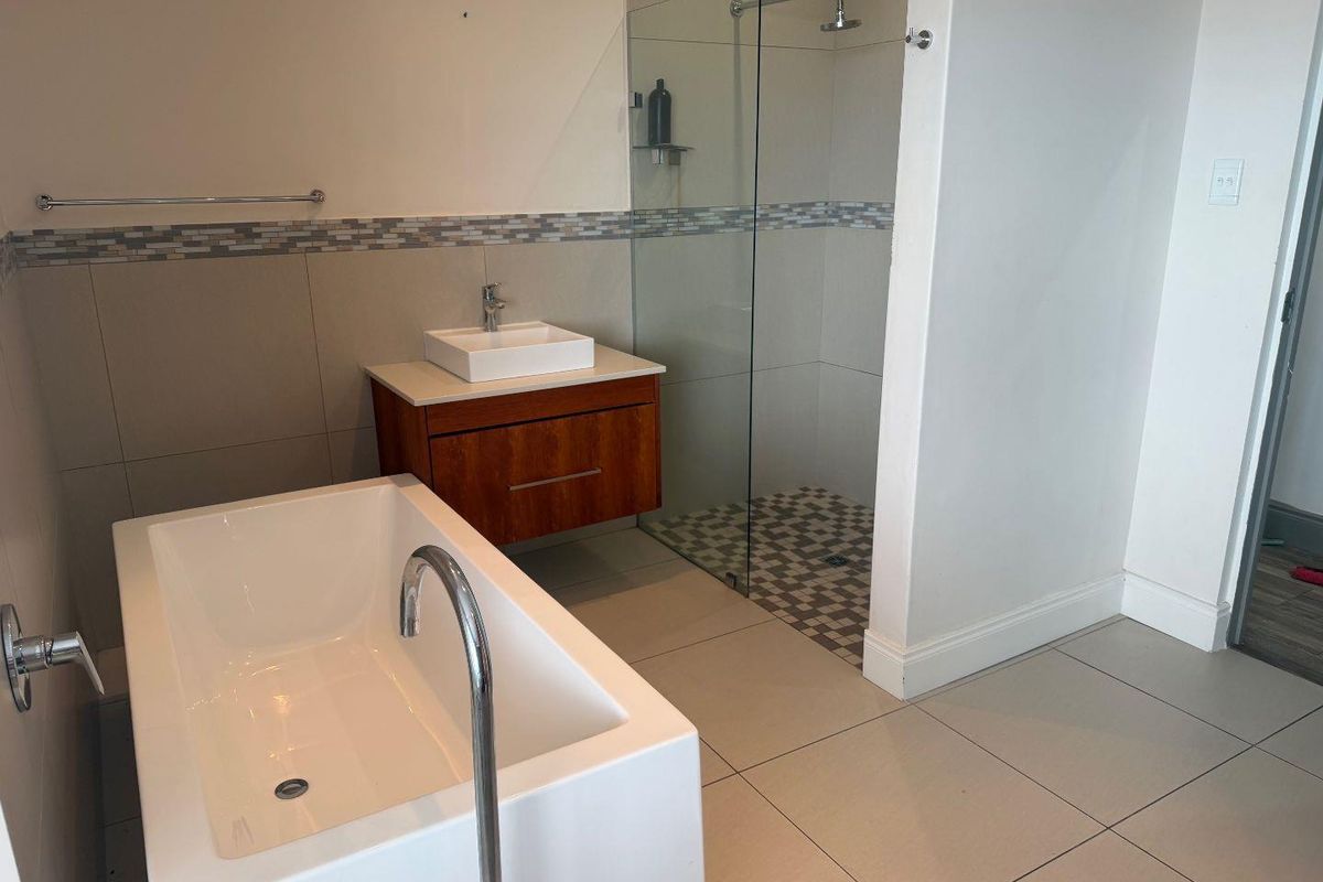 Modern bathroom featuring a freestanding bathtub, a floating vanity with a vessel sink, and a walk-in shower with a glass partition.