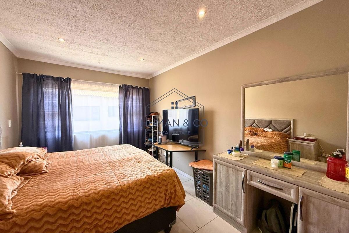 A bedroom featuring tiled flooring, recessed ceiling lighting, and a large window with curtain tracks.