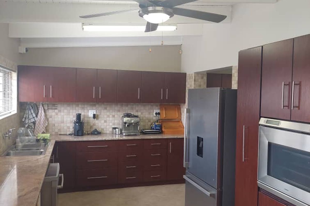 A functional kitchen featuring dark wood cabinetry, granite countertops, tiled backsplash, and built-in oven, complemented by a vaulted ceiling with a central fan.