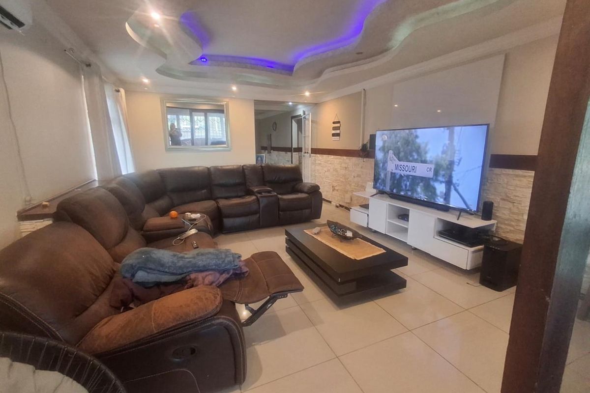 Spacious living room featuring a decorative recessed ceiling with integrated LED lighting, stone veneer accent wall, and neutral tiled flooring.