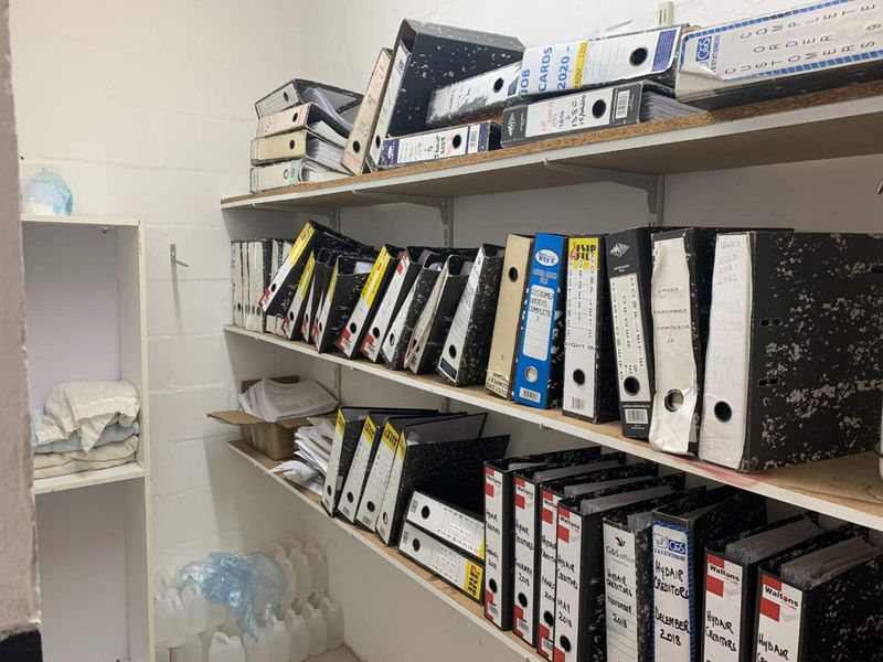 A utility storage area featuring multiple levels of built-in shelving, currently utilized for document and file storage.