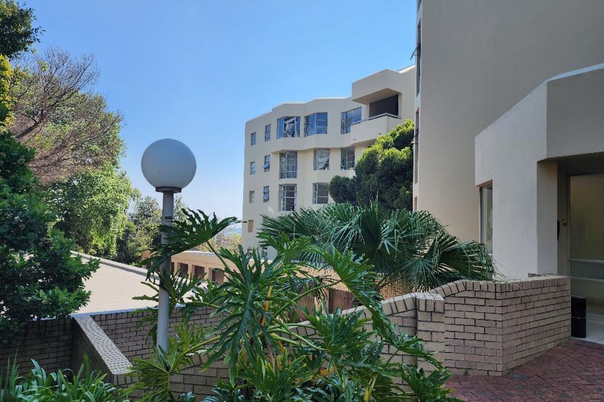 View of the apartment complex exterior featuring brick paved pathways, retaining walls, and established landscaping.