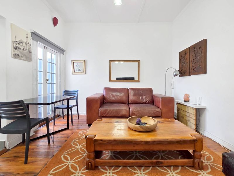 A living room featuring original hardwood flooring and glass-paneled french doors providing natural light and access to the exterior.