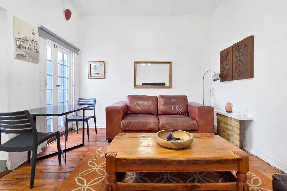 A living room featuring original hardwood flooring and glass-paneled french doors providing natural light and access to the exterior.