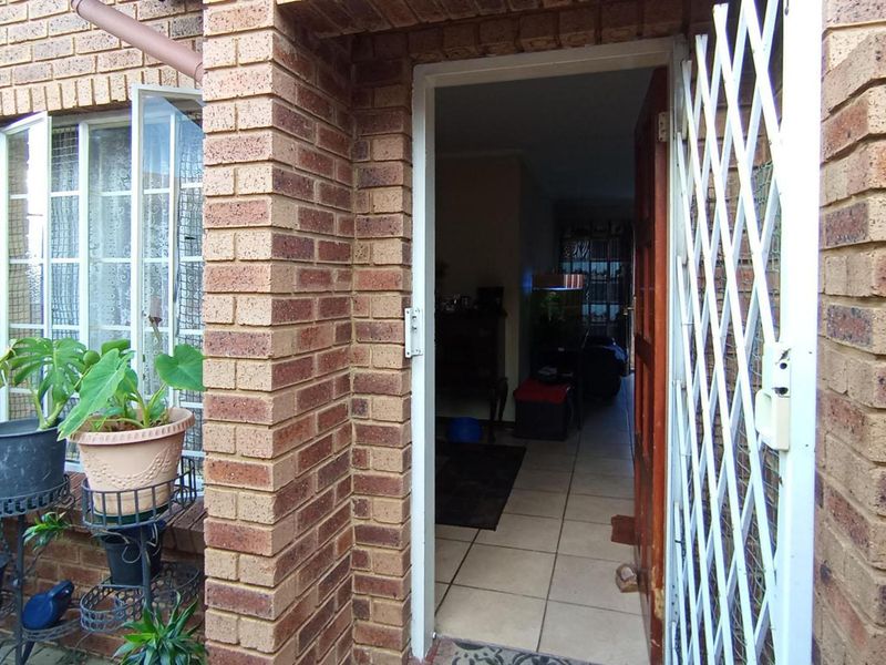 Entrance view of an apartment featuring face brick exterior, a security gate, and tiled flooring leading into the interior living space.