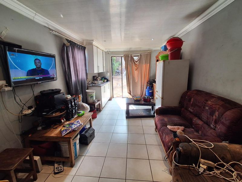 Open-plan living area featuring tiled flooring, kitchen cabinetry, and a sliding glass door leading to the exterior.