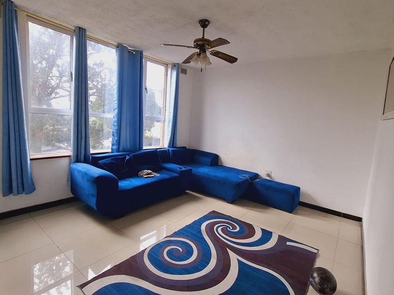 A living room featuring large windows, tiled flooring, and a ceiling fan, offering a bright and functional space ready for modern updates.