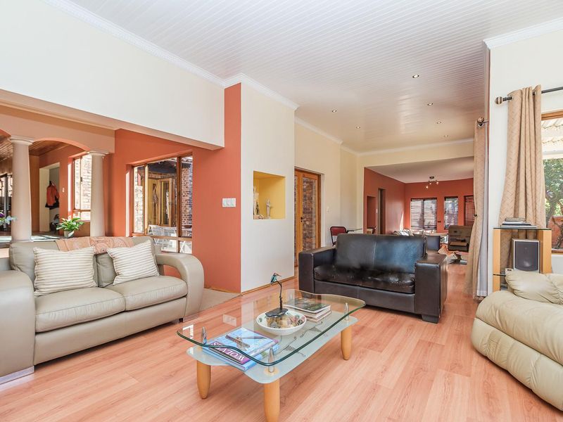Spacious open-plan living area featuring laminate flooring, recessed lighting, and a distinctive architectural archway connecting to adjacent living spaces.