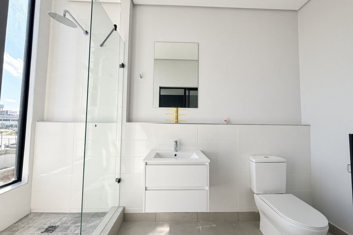 Modern bathroom featuring a glass-enclosed shower, wall-mounted vanity, and neutral tiling, offering a clean and functional space.