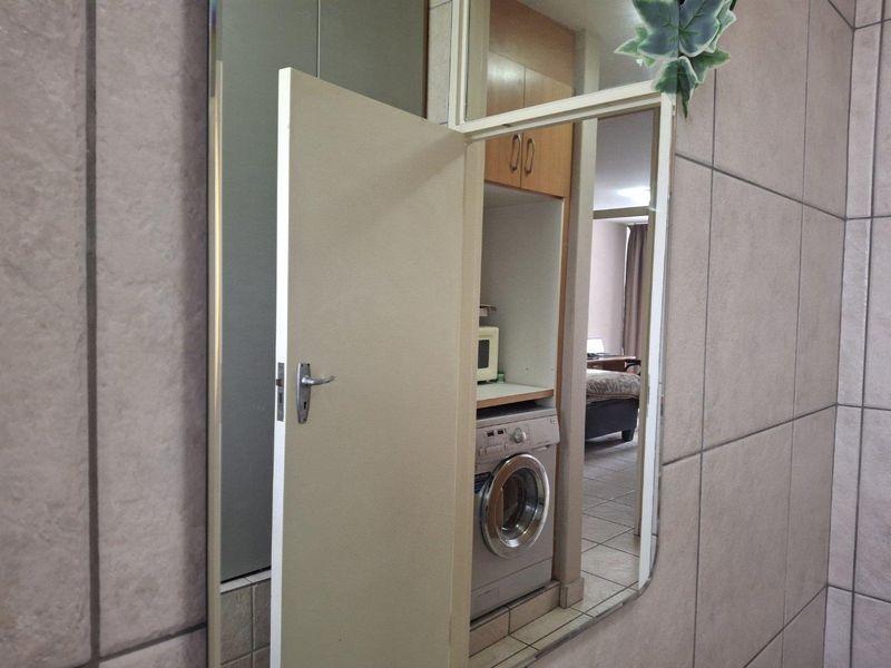 A functional laundry area featuring built-in cabinetry and tiled finishes, providing a dedicated space for laundry appliances.