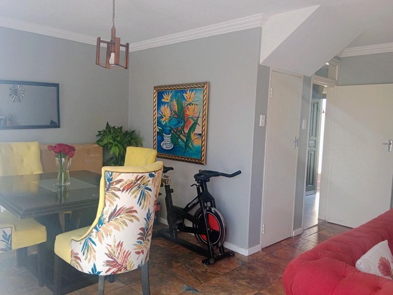 A living area featuring tiled flooring, crown molding, and a pendant light fixture, providing a functional space with access to adjacent rooms.