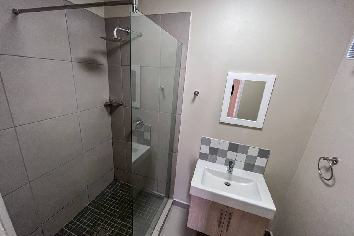 Modern bathroom featuring a glass-enclosed shower with tiled flooring and a vanity cabinet with a basin.