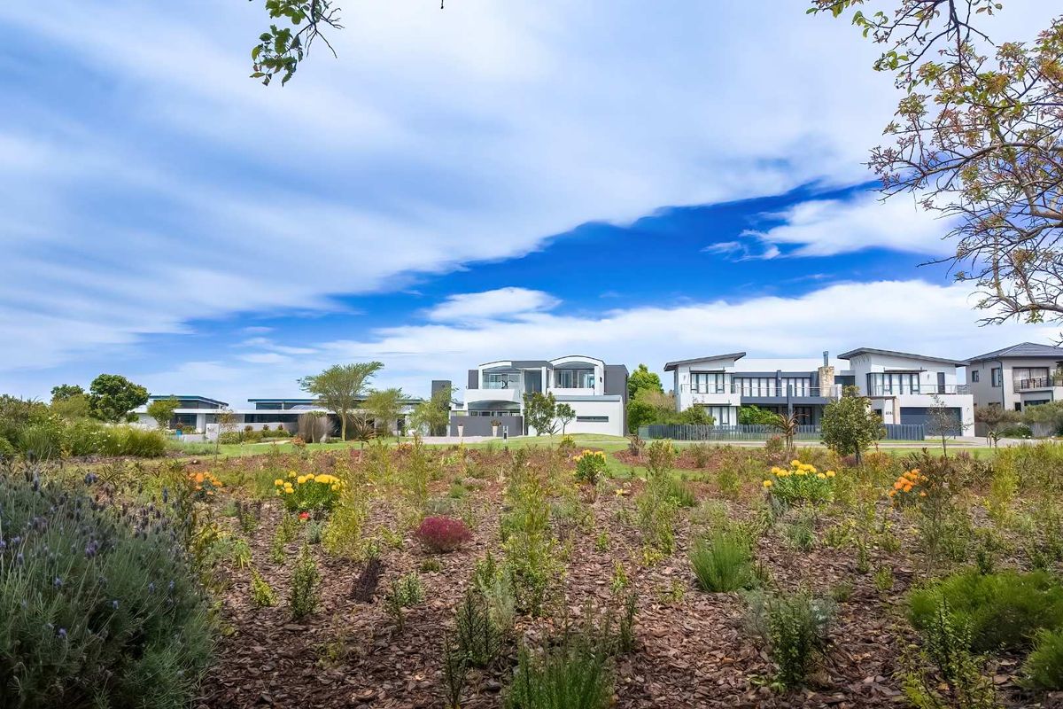 A view of the rear garden area featuring established landscaping and mulched beds, with neighboring residential properties visible in the background.