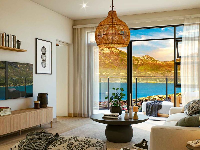 Modern living room featuring large sliding glass doors that open to a balcony with stunning mountain and coastal views.