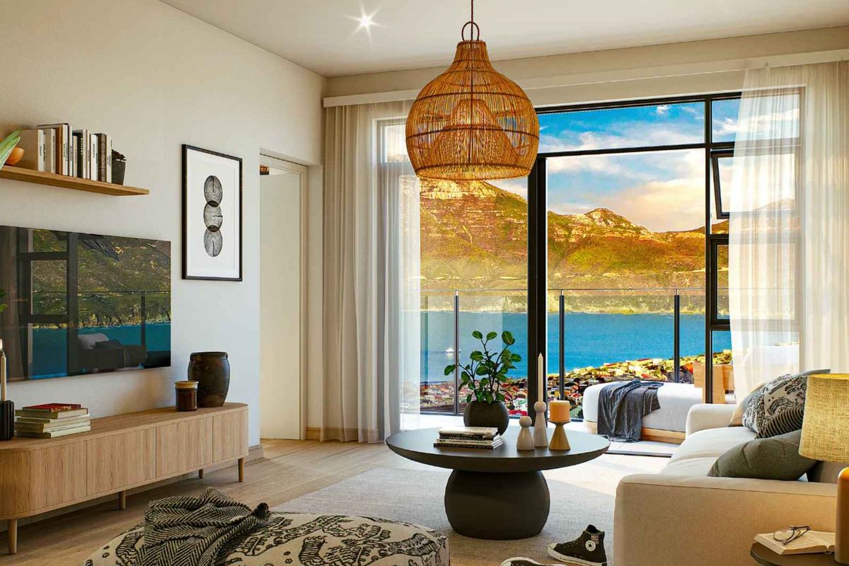 Modern living room featuring large sliding glass doors that open to a balcony with stunning mountain and coastal views.
