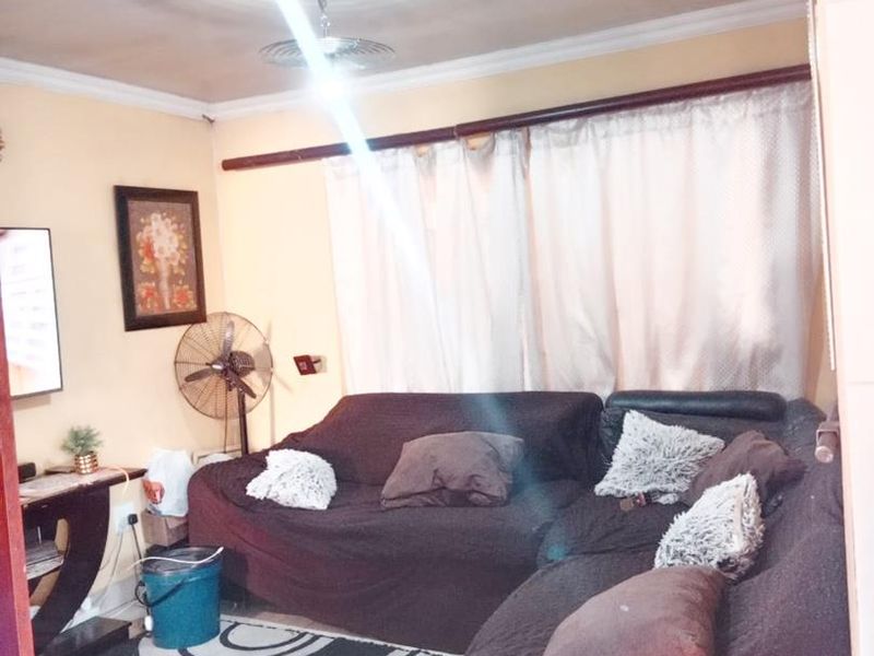 A living room space featuring ceiling cornicing and a central light fixture, viewed from the doorway.