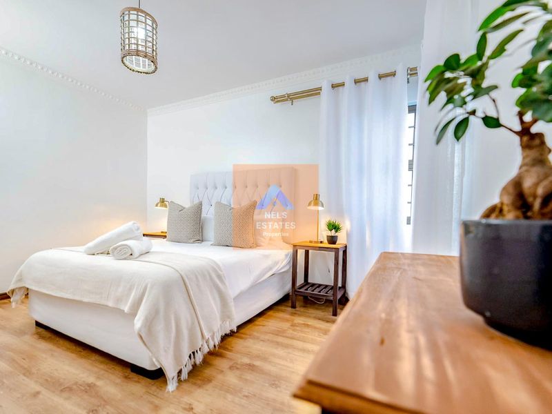 A well-maintained bedroom featuring light wood-look laminate flooring and decorative ceiling cornicing, creating a bright and inviting atmosphere.