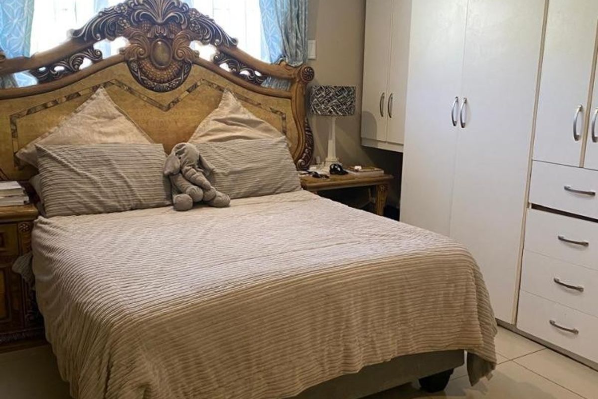 A bedroom featuring tiled flooring, recessed downlights, and extensive built-in cupboard storage.