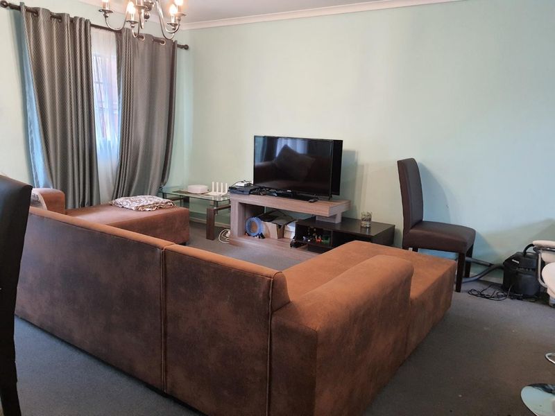 A living room featuring carpet flooring, coving, and curtain rails, providing a functional space for relaxation.