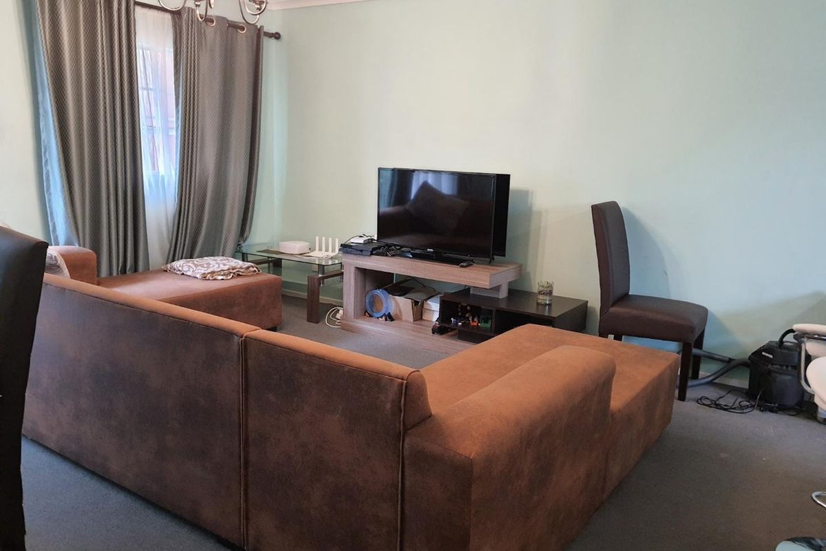 A living room featuring carpet flooring, coving, and curtain rails, providing a functional space for relaxation.