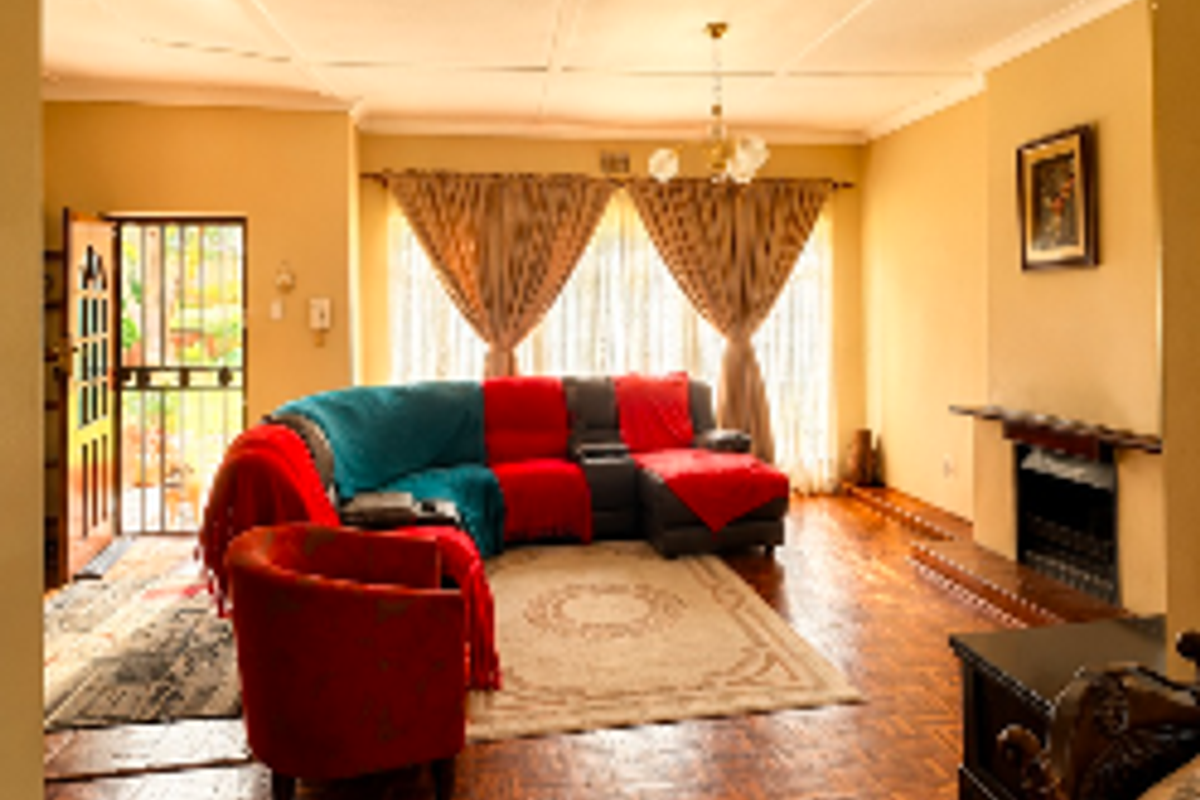 Spacious living room featuring traditional parquet flooring, a built-in fireplace, and direct access to the exterior through a security gate.