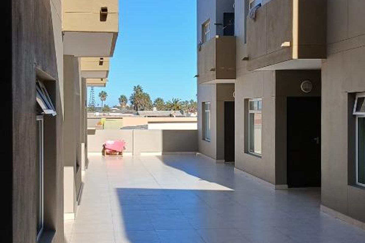 A view of the apartment complex exterior walkway featuring tiled flooring and modern building facades.