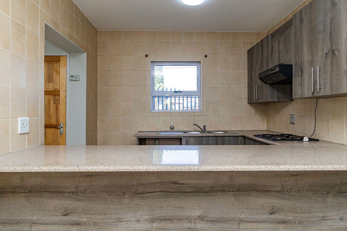 A functional kitchen featuring granite countertops, built-in cabinetry, a double sink, and a built-in hob with an extractor fan.