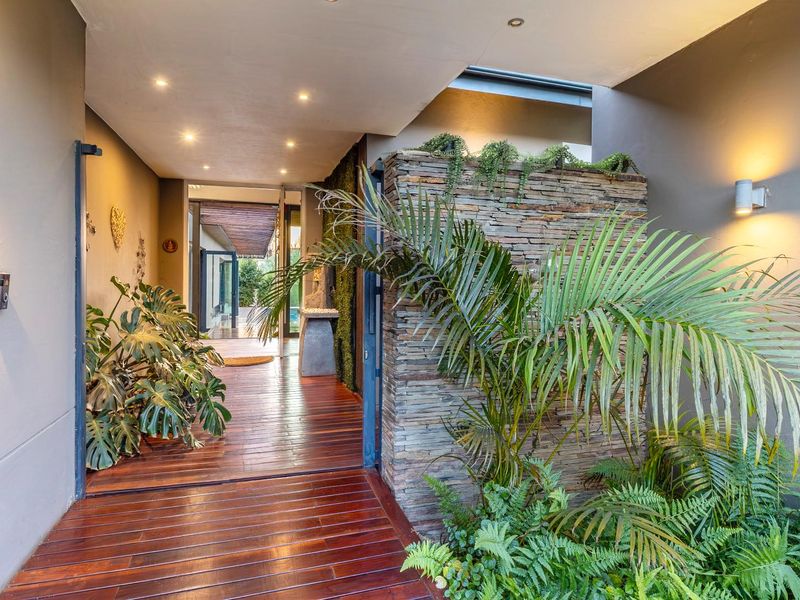 A modern, welcoming entrance featuring timber decking, a striking stacked stone feature wall, and integrated vertical garden elements under a skylight.