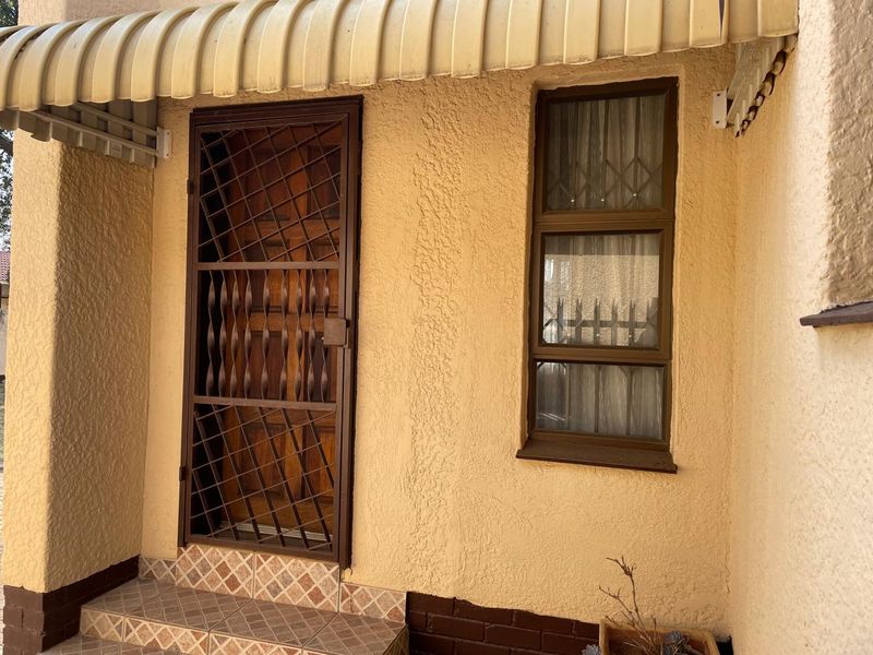Front entrance area featuring a security gate, protective awning, and tiled step, providing a functional and secure access point to the home.