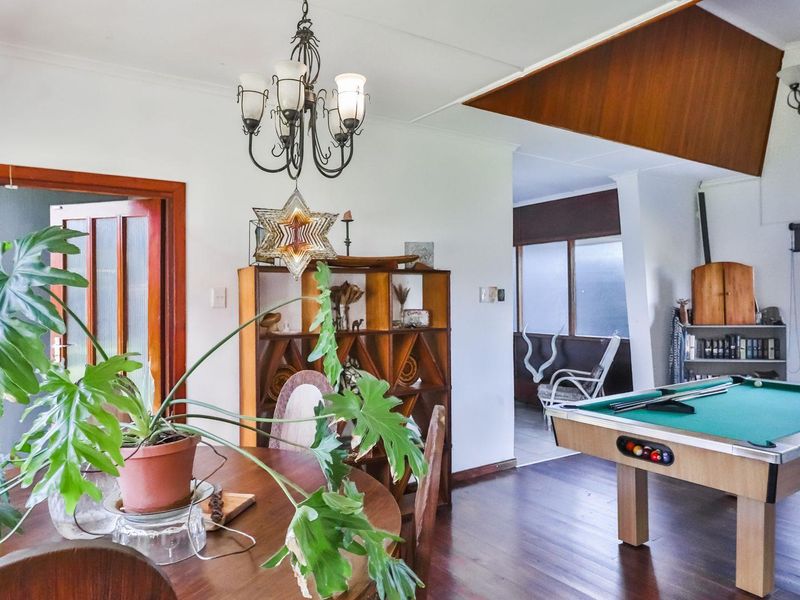 Spacious living area featuring timber flooring, a vaulted ceiling detail, and a classic chandelier, offering a versatile layout for relaxation and entertainment.