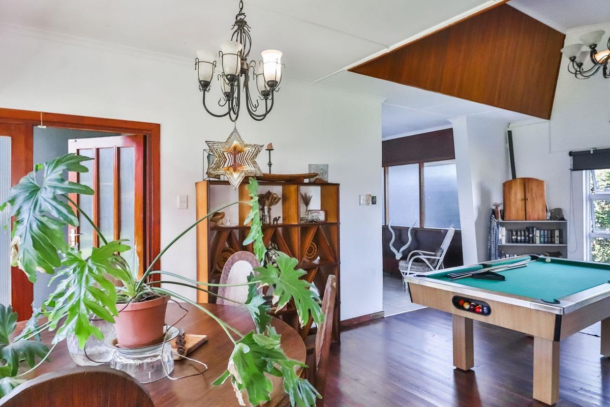 Spacious living area featuring timber flooring, a vaulted ceiling detail, and a classic chandelier, offering a versatile layout for relaxation and entertainment.