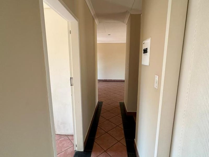 A vacant interior hallway featuring tiled flooring and recessed ceiling lighting, providing access to adjacent rooms within the townhouse.