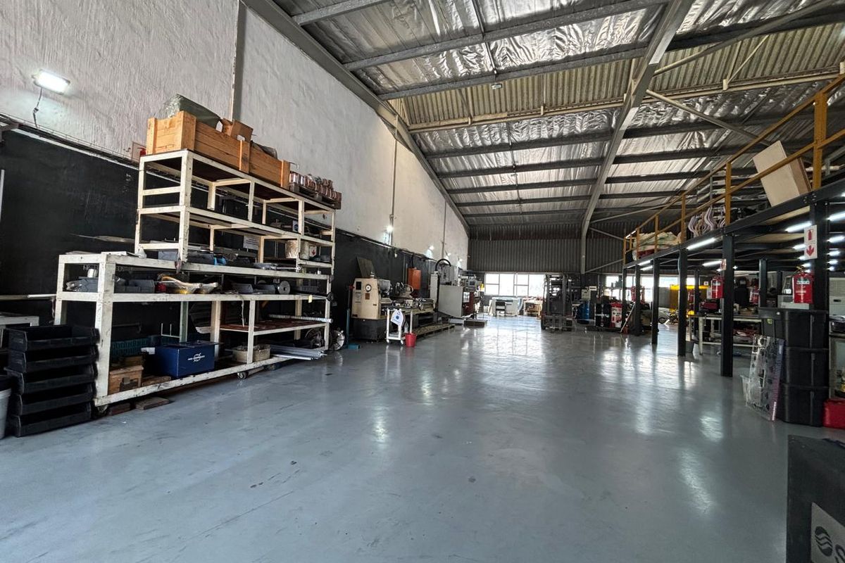 Spacious industrial warehouse featuring high ceilings with exposed steel trusses, durable epoxy flooring, and a functional mezzanine level for additional storage or workspace.