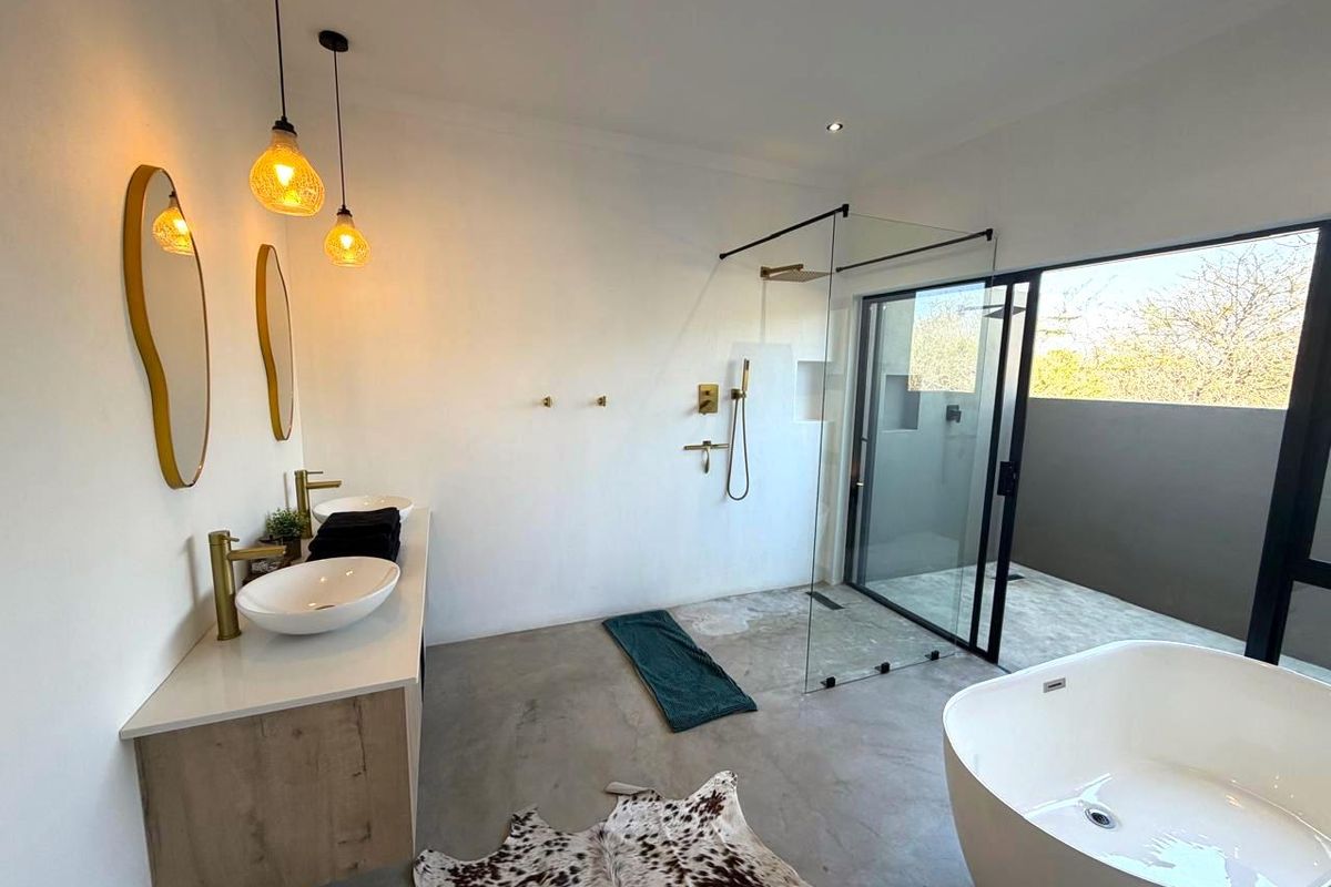 Modern bathroom featuring a double vanity with vessel sinks, a spacious walk-in shower with glass screen, and a contemporary freestanding bathtub on concrete floors.
