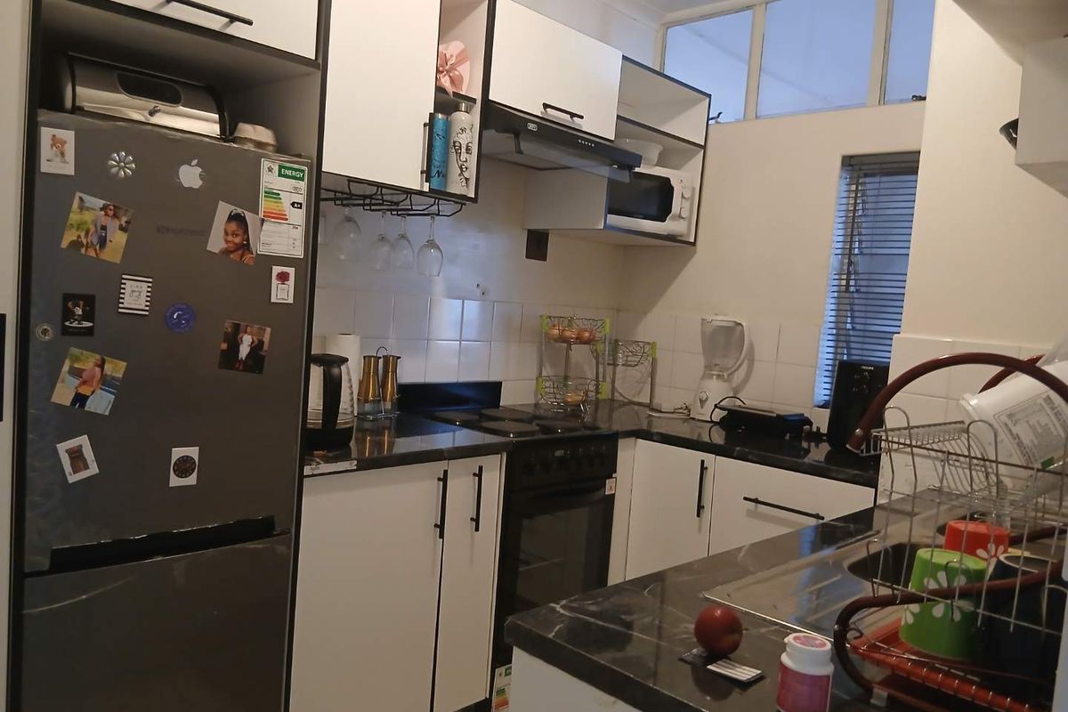 A functional kitchen featuring white cabinetry, dark stone countertops, built-in oven and stove, and a tiled backsplash with natural light from a side window.