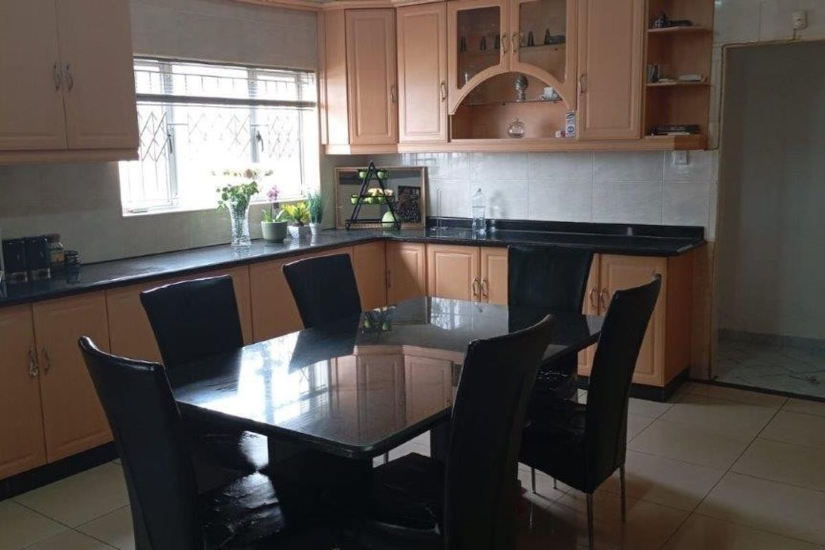 A functional kitchen featuring light wood-tone cabinetry, dark granite countertops, and tiled flooring, offering a practical layout for daily meal preparation.