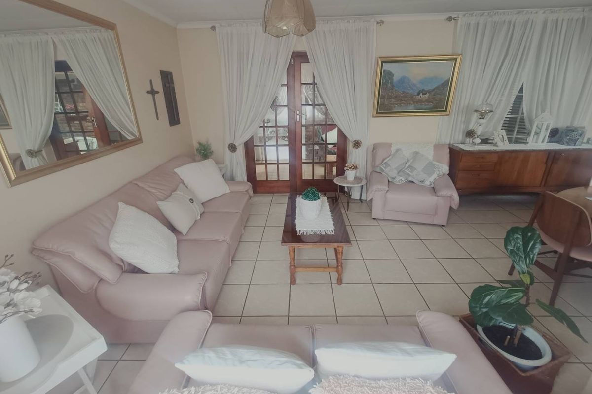 A comfortable living room featuring tiled flooring and double glass-paneled doors providing access to the outdoor area.