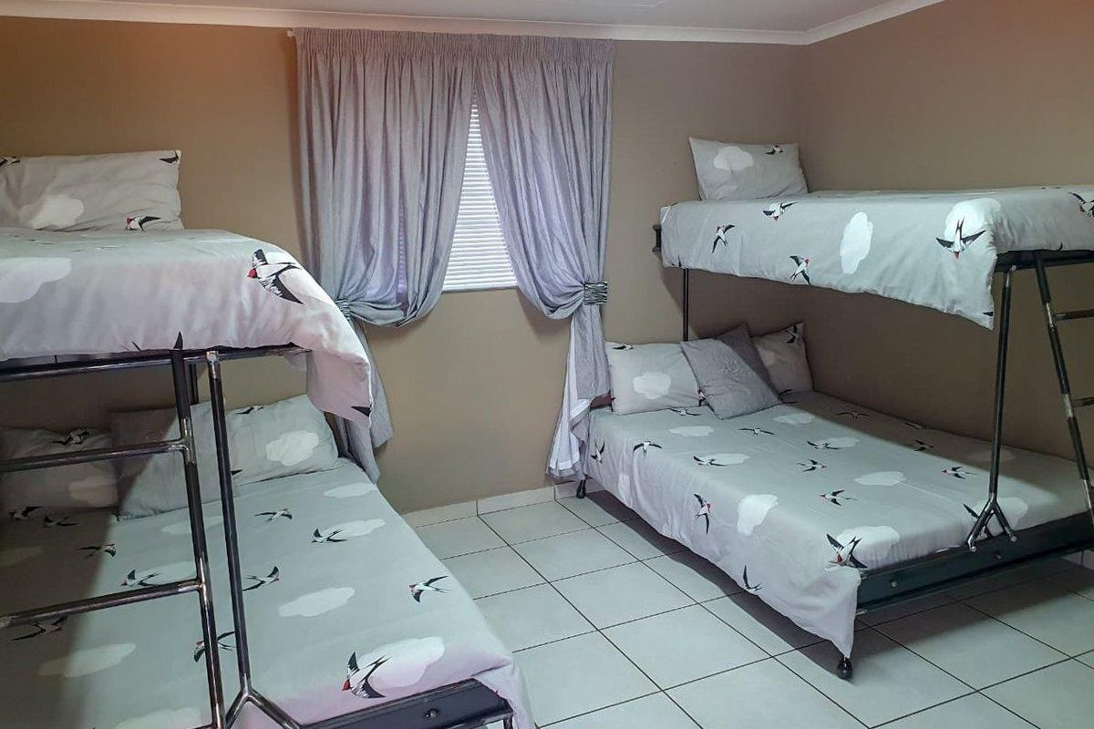 A functional bedroom featuring tiled flooring and a window with curtain treatments, currently configured with two bunk beds.