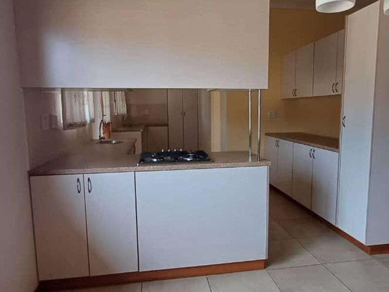 A clean, functional kitchen featuring light-toned cabinetry, a gas hob, laminate countertops, and tiled flooring, offering a bright and practical workspace.