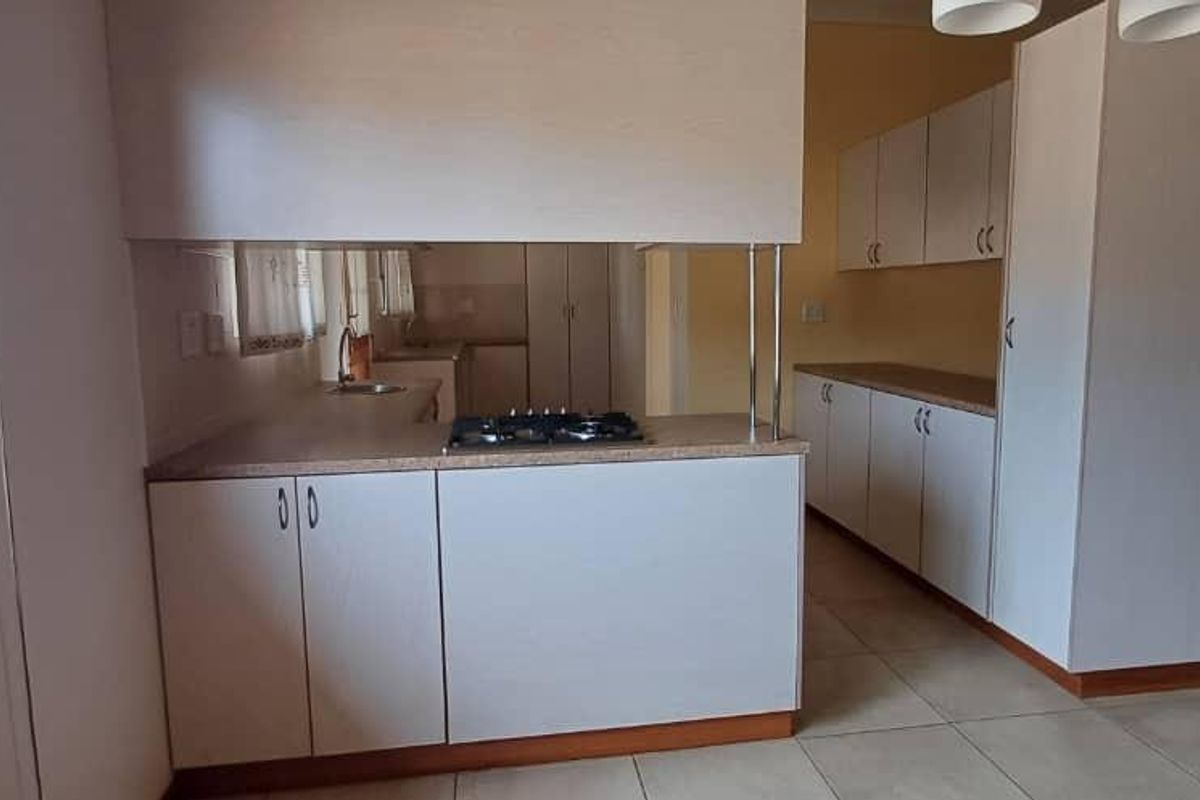 A clean, functional kitchen featuring light-toned cabinetry, a gas hob, laminate countertops, and tiled flooring, offering a bright and practical workspace.