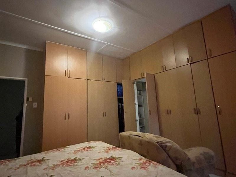 A bedroom featuring extensive wall-to-wall built-in wooden cupboards providing ample storage space.