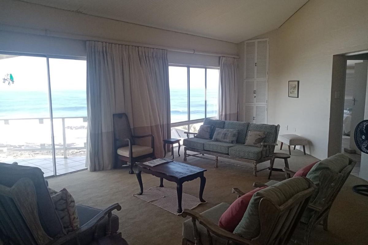 Spacious living room featuring vaulted ceilings, built-in storage, and large sliding glass doors offering expansive ocean views.