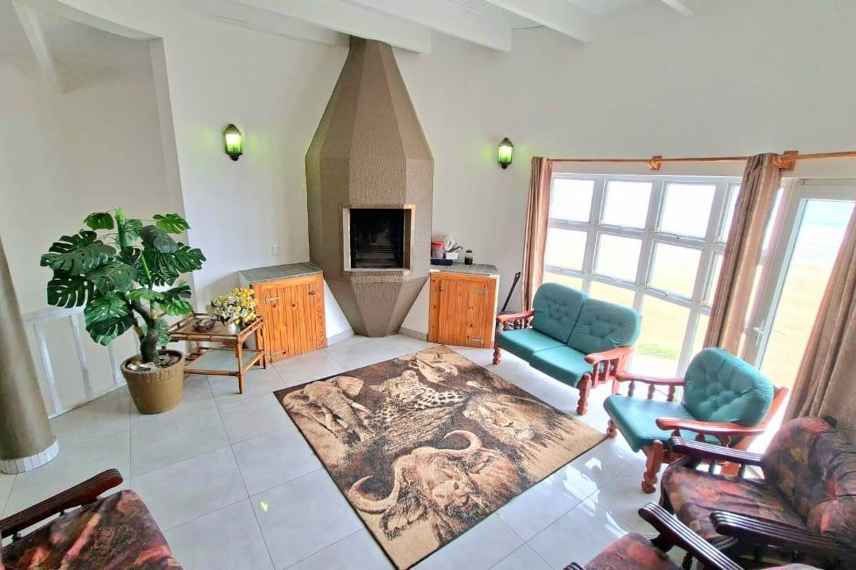 A living room featuring a unique geometric built-in fireplace, tiled flooring, and large windows providing natural light and outdoor views.