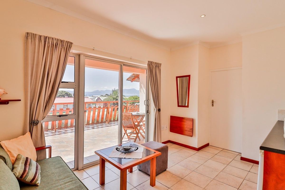 A bright living area featuring tiled flooring and large sliding glass doors that open onto a spacious balcony with scenic views.