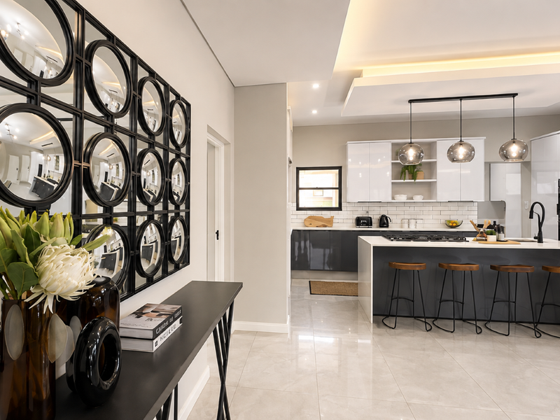 Modern open-plan kitchen featuring a central island, sleek gloss cabinetry, integrated appliances, and elegant recessed ceiling lighting with high-quality tiled flooring.