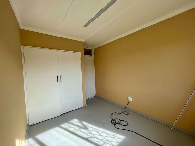 An empty bedroom featuring built-in cupboards, tiled flooring, and neutral wall paint, offering a blank canvas for personalization.