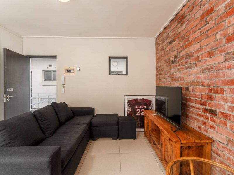 Living room featuring a prominent exposed brick feature wall and neutral tiled flooring, providing a warm and textured aesthetic.