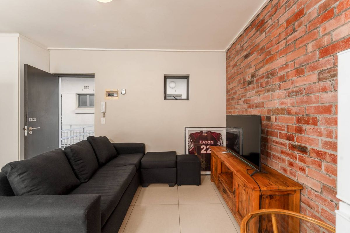 Living room featuring a prominent exposed brick feature wall and neutral tiled flooring, providing a warm and textured aesthetic.