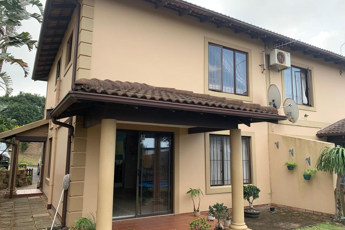 Rear view of the townhouse featuring a covered tiled patio, concrete columns, and access via a sliding glass door.